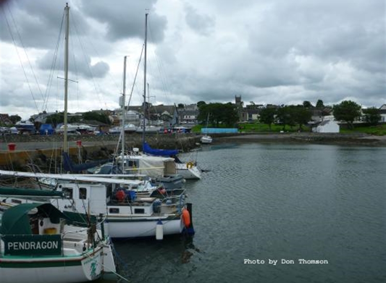 Resident boats on pier with a visitor in the distance against the wall