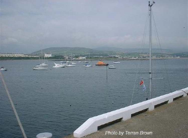 Port St Mary. Looking NE from Outer Pier. Note SH Perch foreground & visting yacht mast...